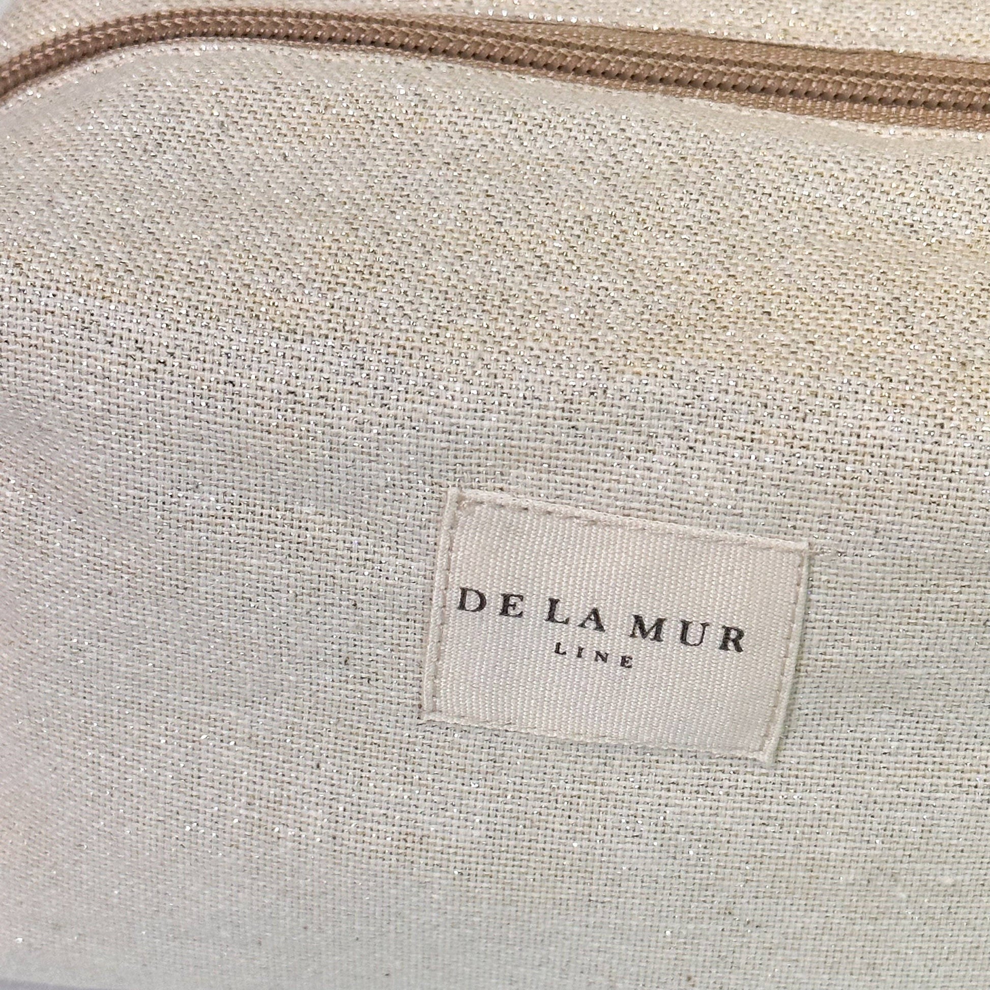 Dettaglio del tessuto beige con fili lurex dorati e argentati, finitura naturale e raffinata.