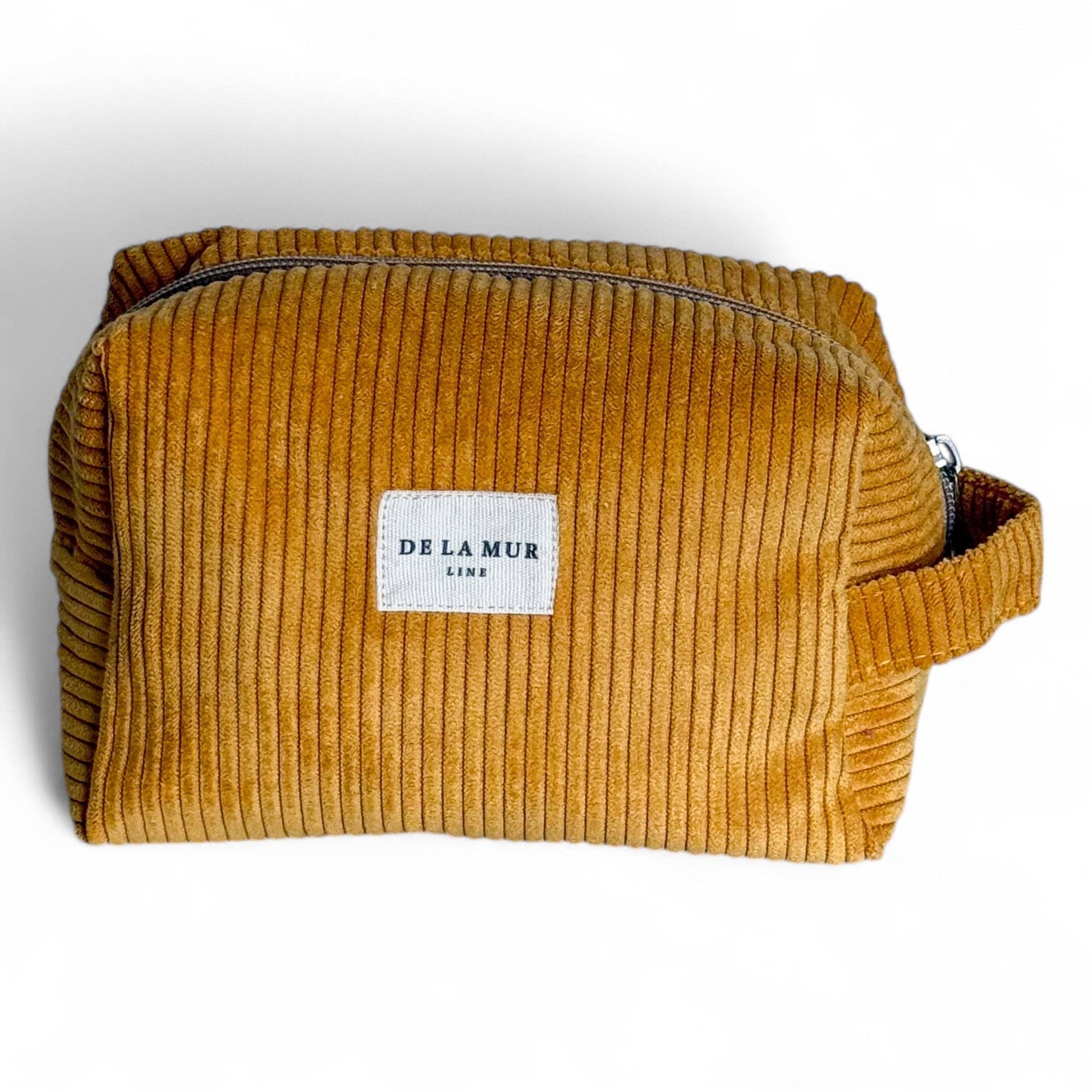 Beauty case in velluto a coste color senape con manico laterale.