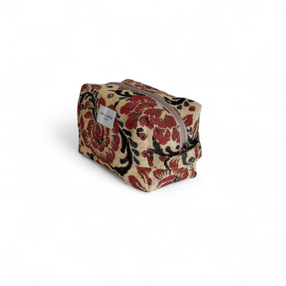 Beauty case in tessuto jacquard floreale beige e rosso con manico laterale.
