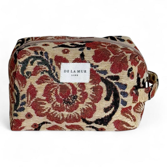 Beauty case in tessuto jacquard floreale beige e rosso con manico laterale.