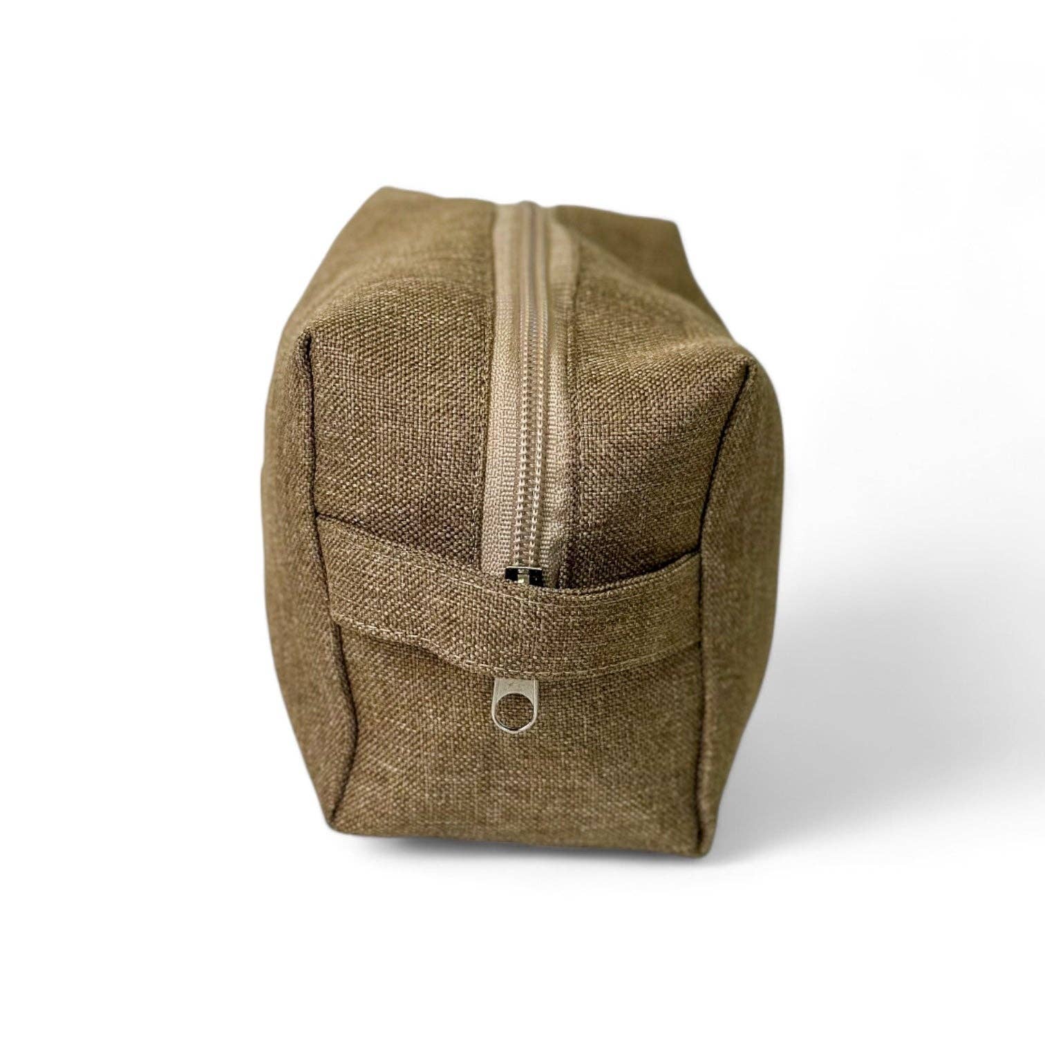 Vista laterale del beauty case ocra in tessuto spesso, con manico laterale e chiusura a zip, ideale come porta trucchi da viaggio.