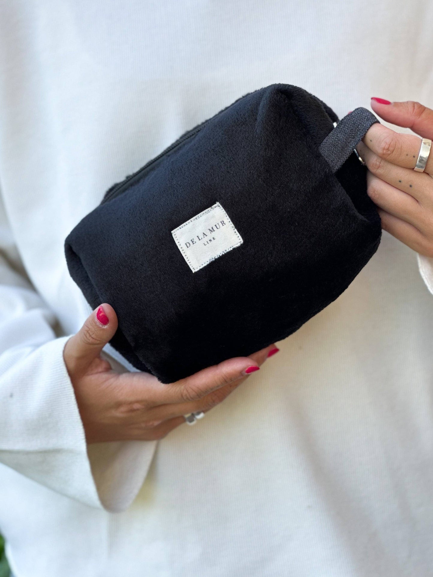 Beauty case in pelo nero, accessorio elegante e naturale per il trucco e la cura personale.
