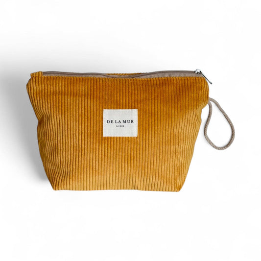 Beauty case in velluto a coste color senape con manico in corda beige e cerniera superiore.