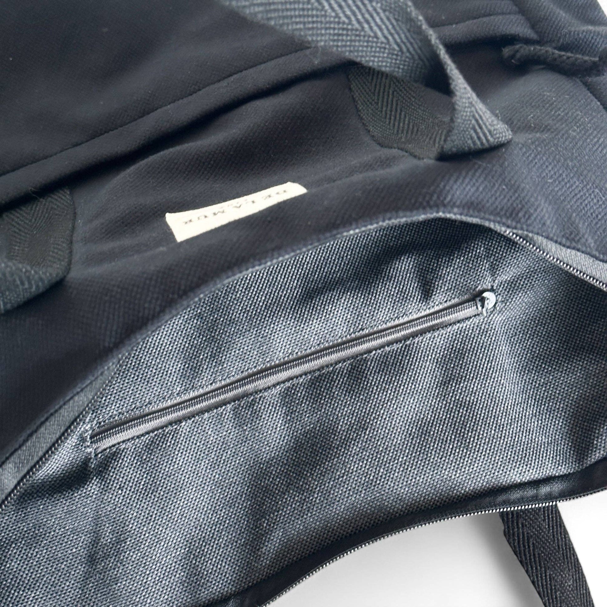 Interno dello zaino in velluto nero con tasca e cerniera.